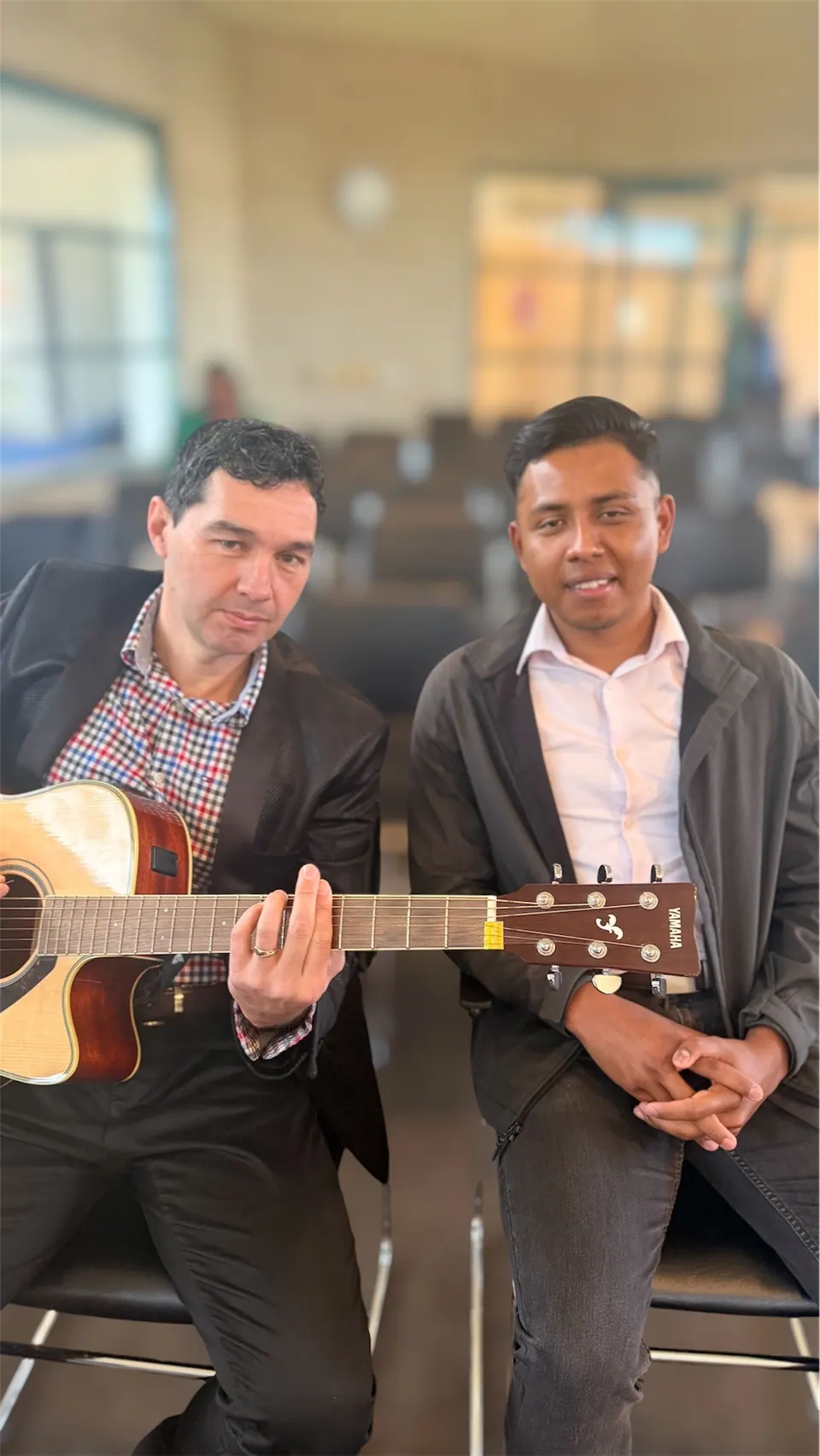 Dos hombres sentados juntos con una guitarra acústica