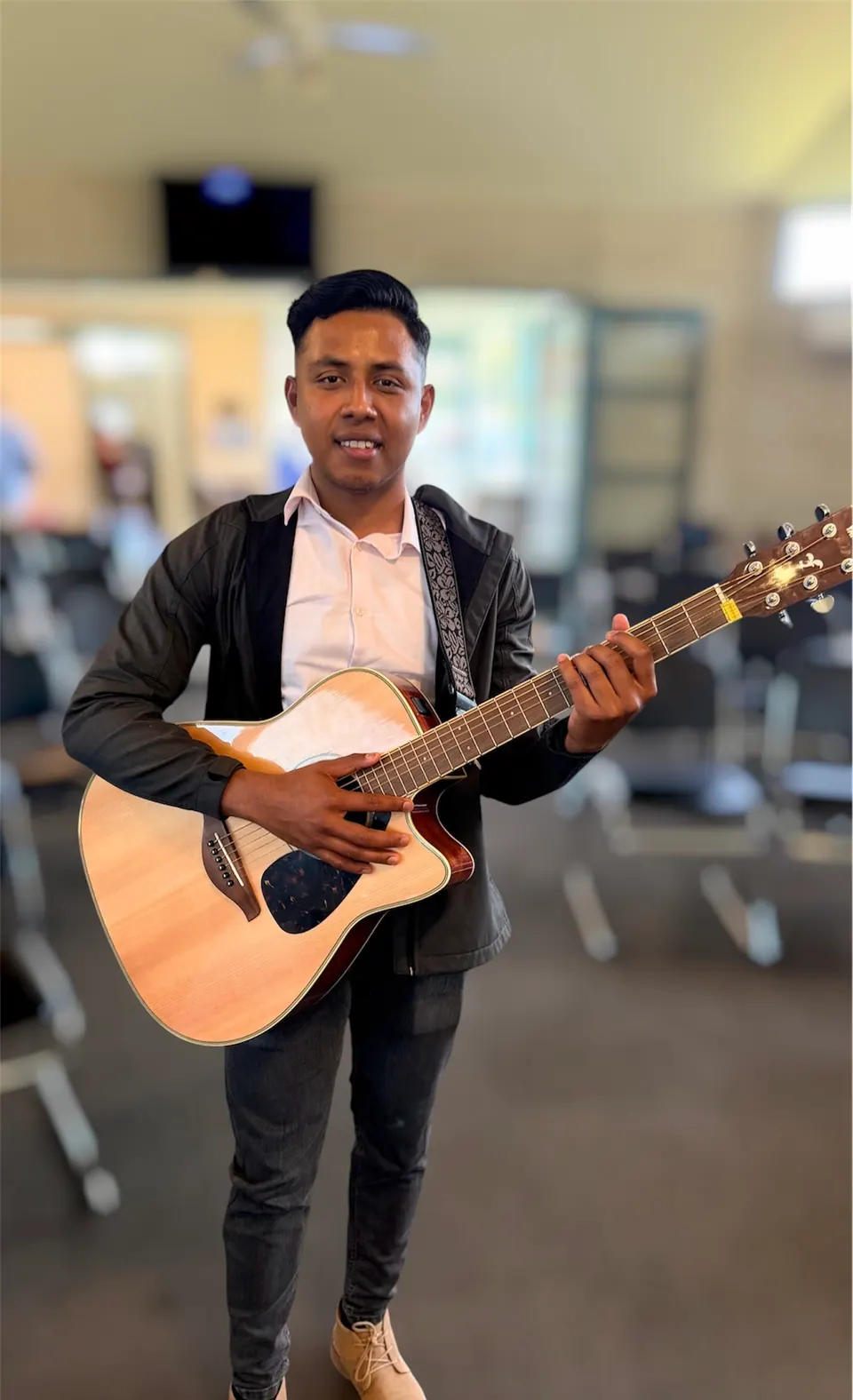 Un hombre sosteniendo una guitarra acústica